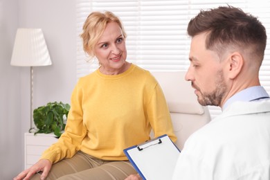 Photo of Doctor with clipboard consulting patient in clinic