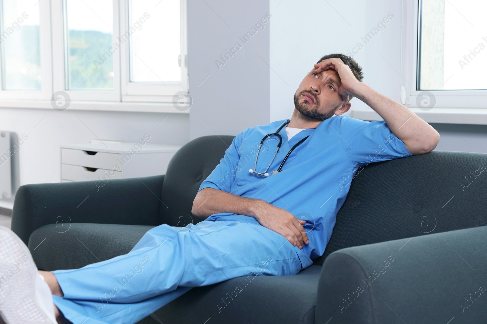 Photo of Exhausted doctor resting on sofa in hospital