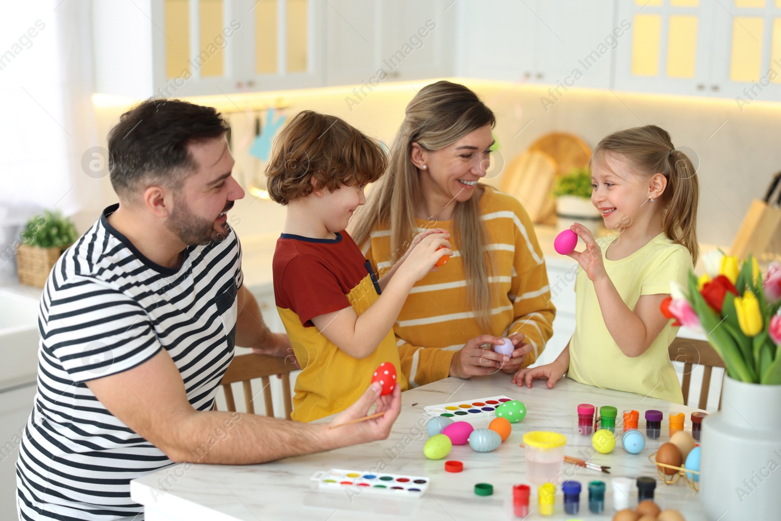 Photo of Happy Easter. Cute family with painted eggs at white marble table in kitchen