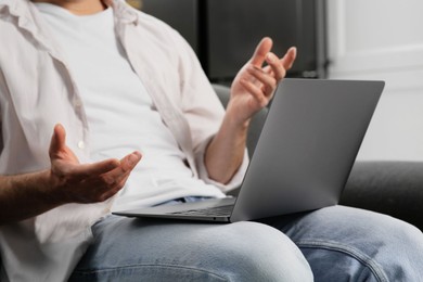 Man having video chat via laptop indoors, closeup