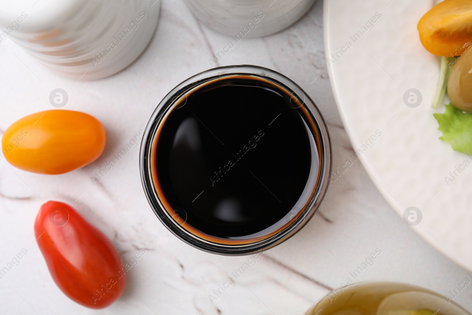 Photo of Tasty vinegar in bowl and tomatoes on light textured table, flat lay