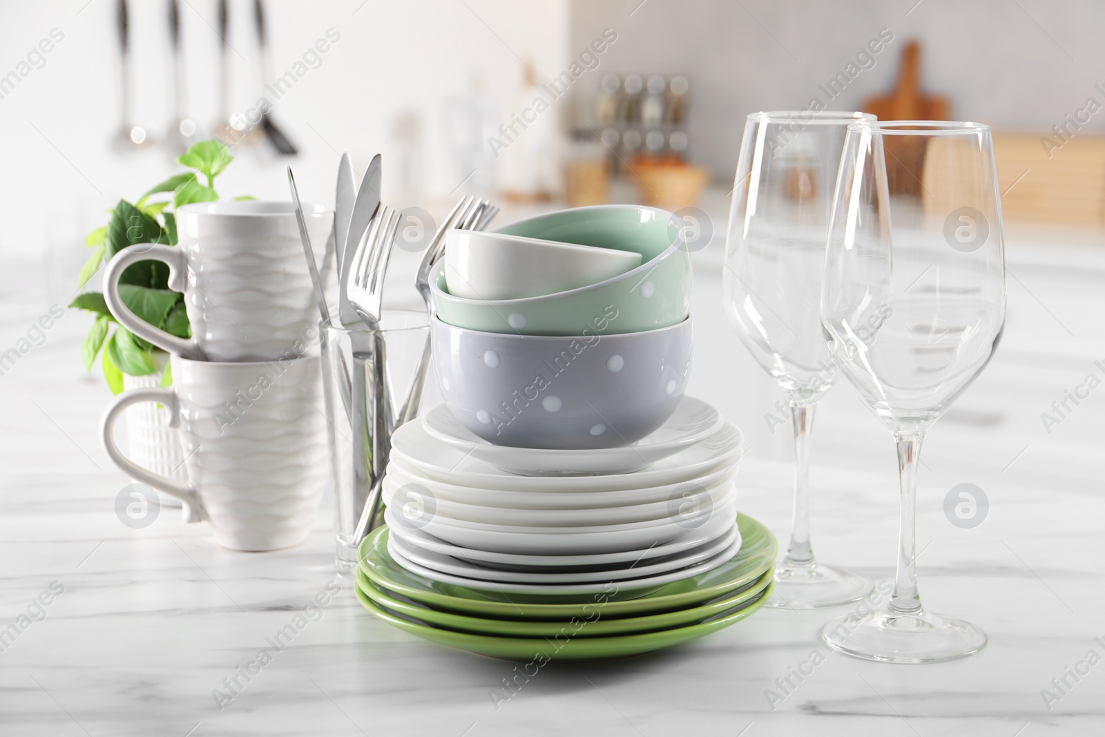 Photo of Many different clean dishware, glasses, cups and cutlery on white marble table indoors