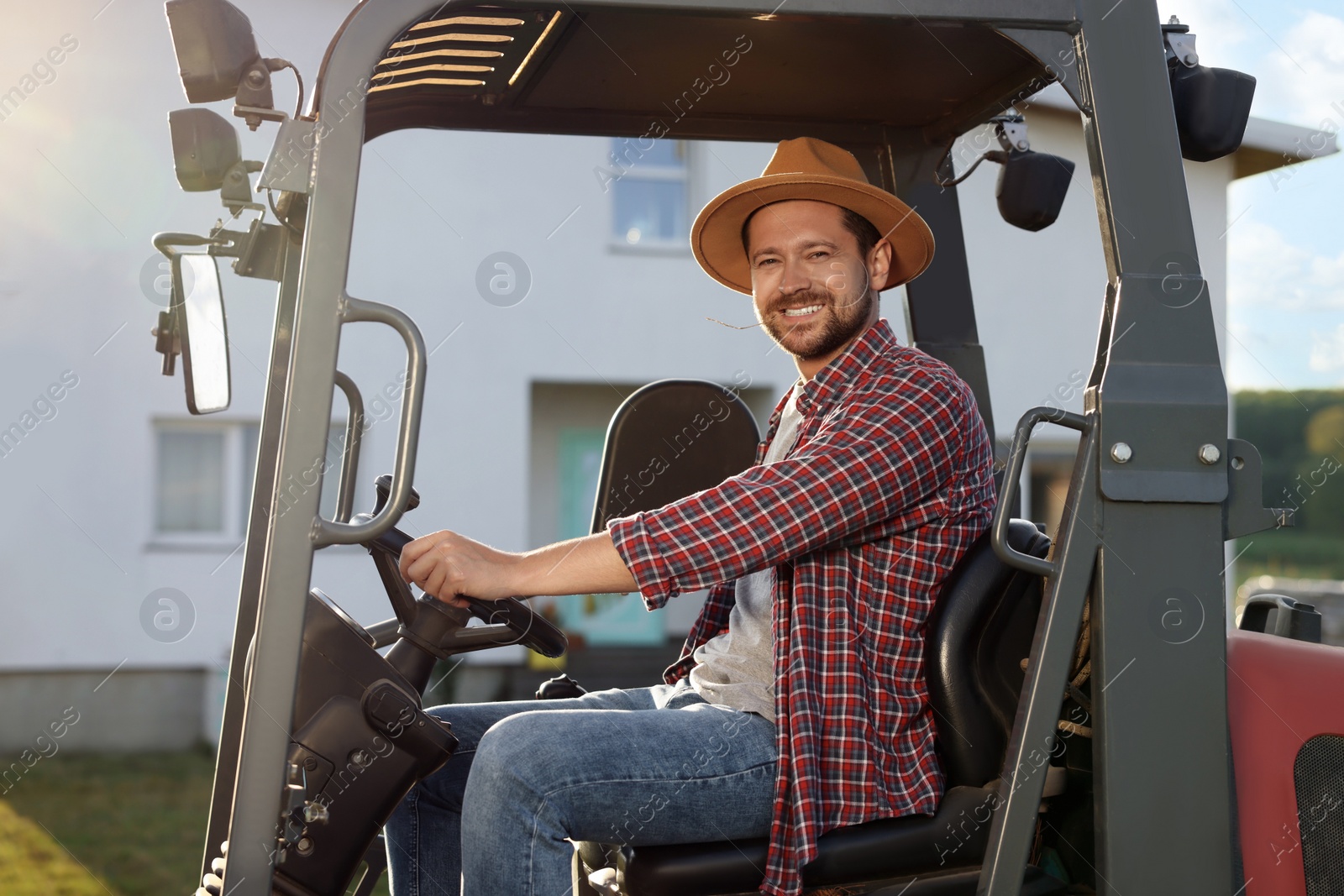 Photo of Smiling farmer driving loader outdoors. Agriculture equipment