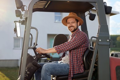 Photo of Smiling farmer driving loader outdoors. Agriculture equipment