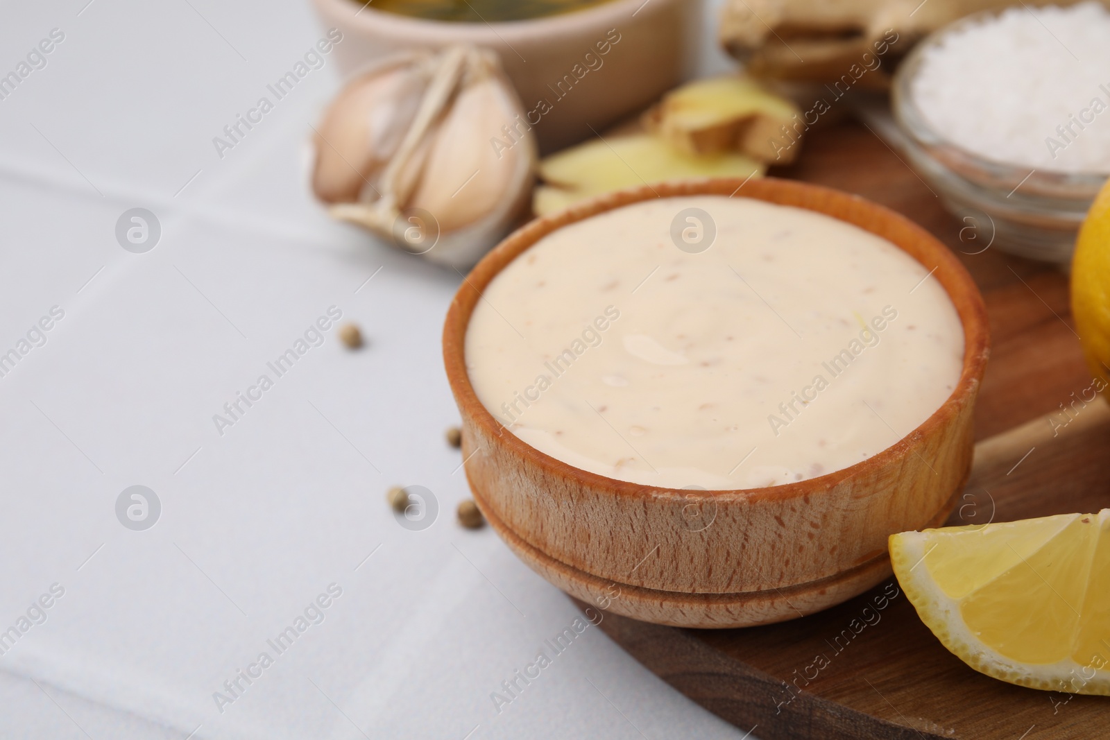 Photo of Fresh marinade and ingredients on white tiled table, closeup. Space for text