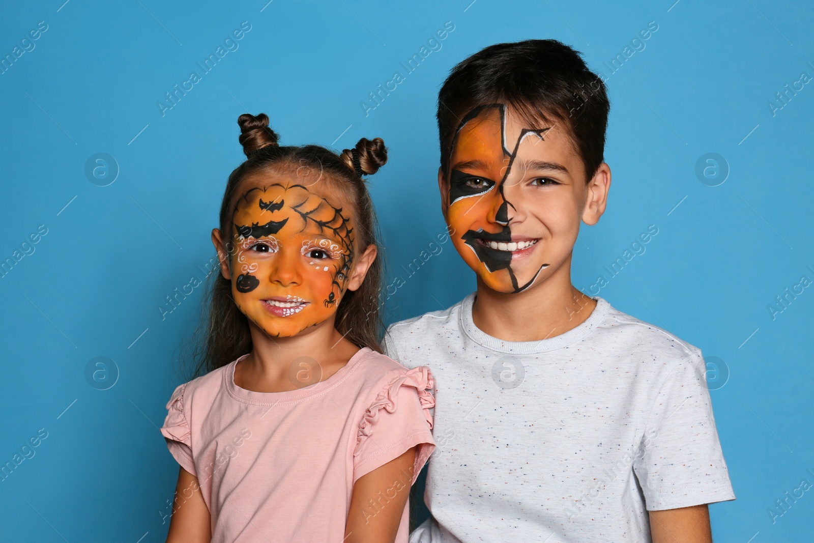 Photo of Cute little children with face painting on blue background