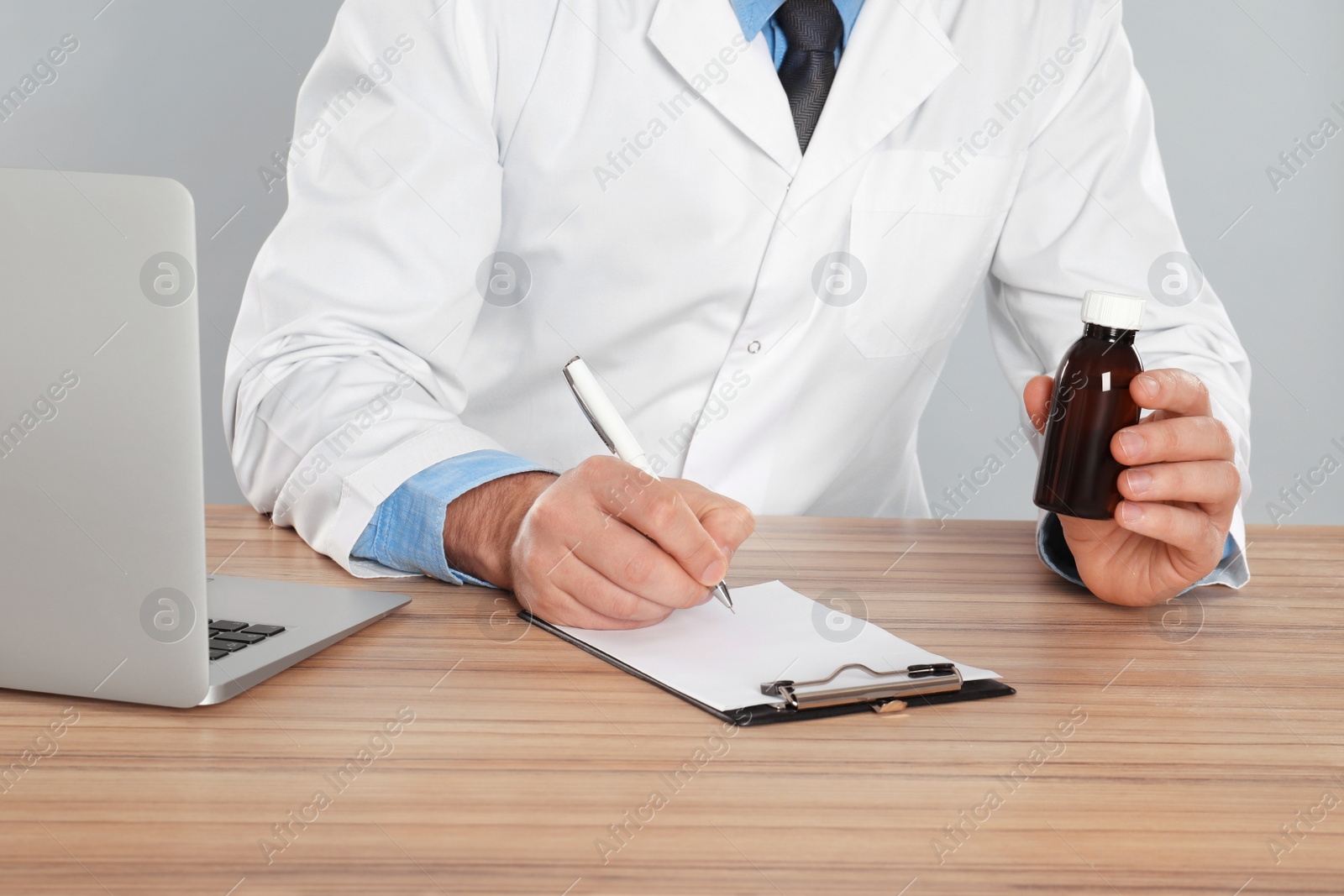 Photo of Professional pharmacist working at table against light grey background, closeup