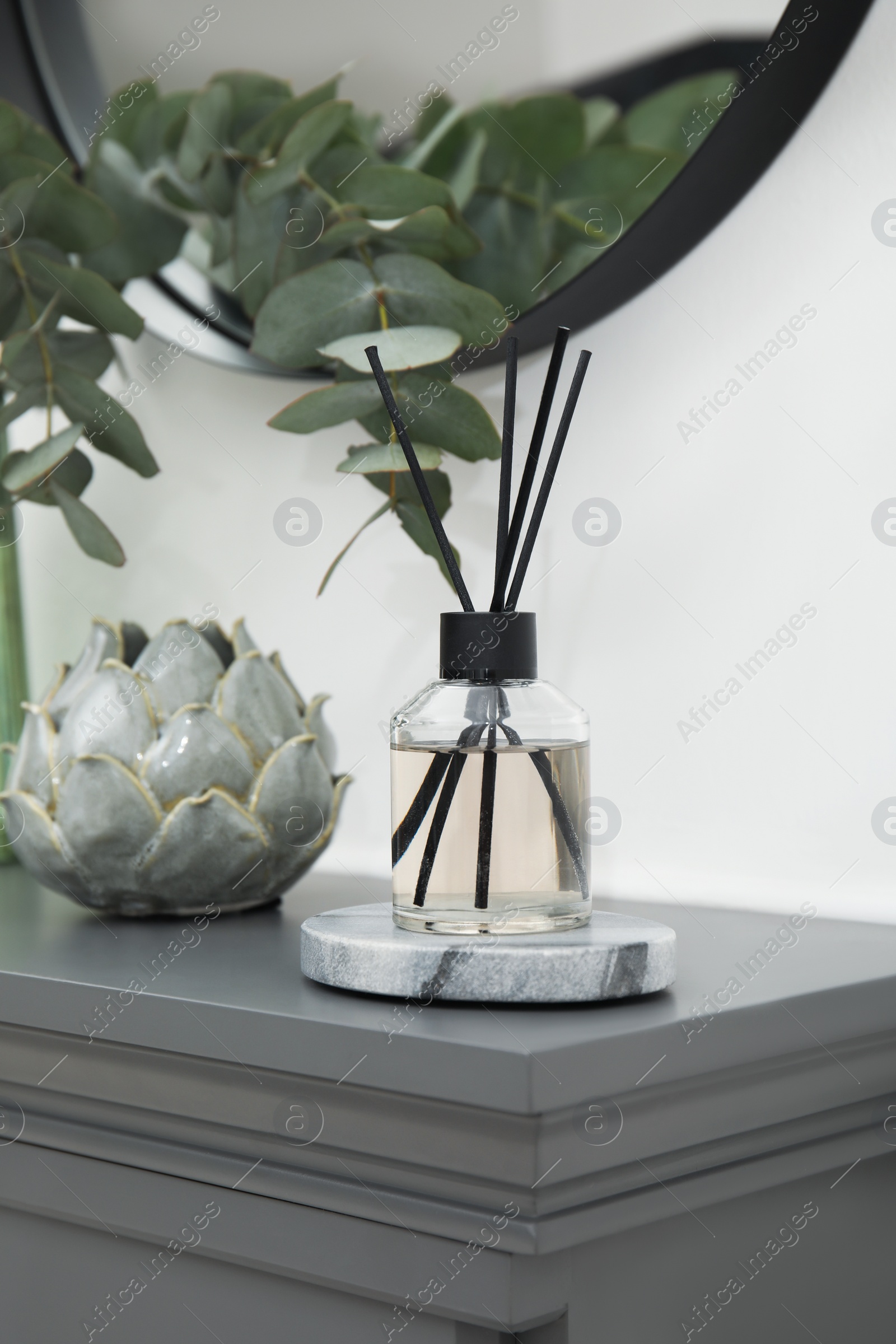 Photo of Reed diffuser and home decor on grey table near white wall