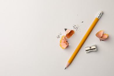 Photo of Graphite pencil, shavings and sharpener on white background, flat lay. Space for text