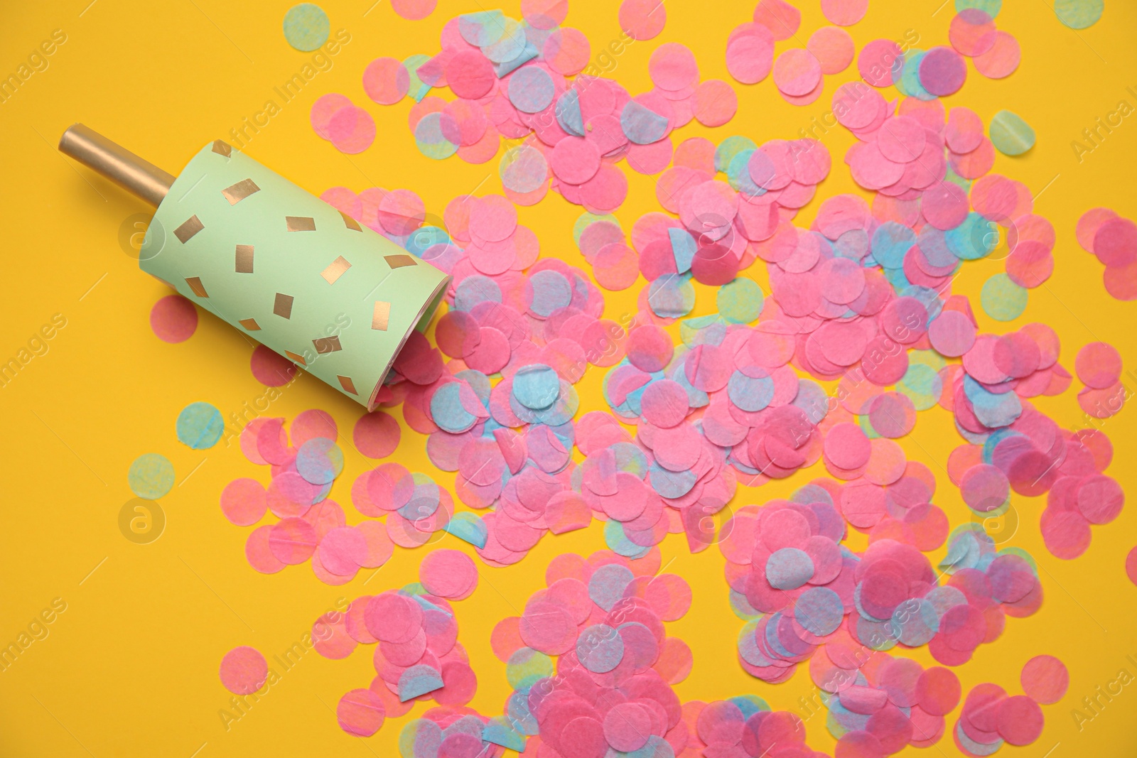 Photo of Party popper with bright confetti on orange background, flat lay