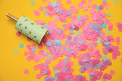 Photo of Party popper with bright confetti on orange background, flat lay