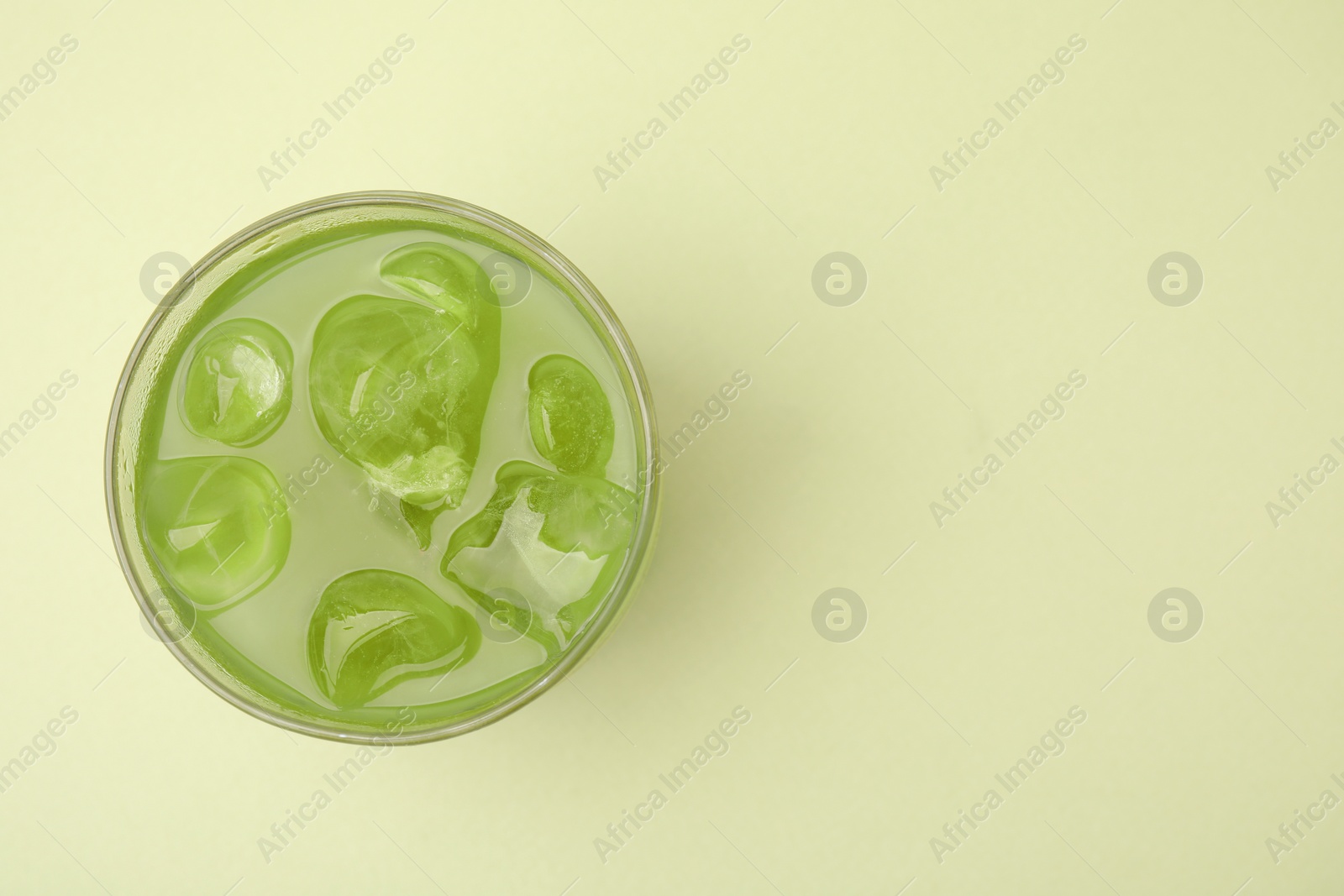 Photo of Glass of delicious iced matcha tea on green background, top view. Space for text