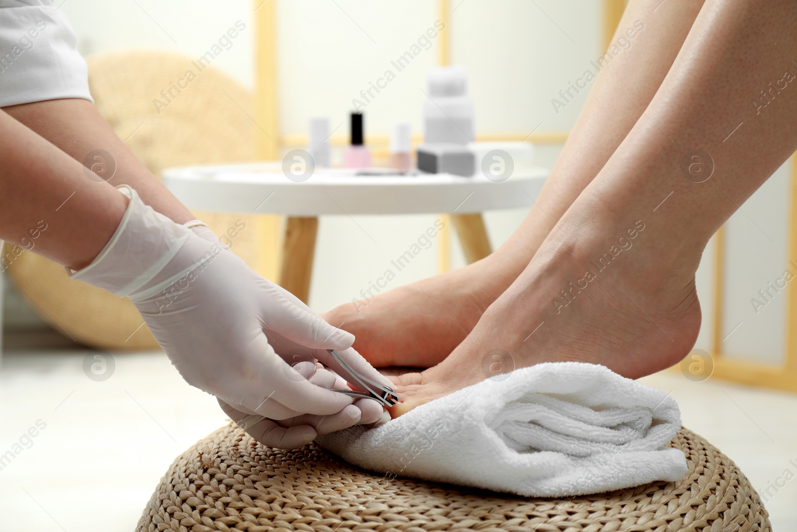 Photo of Professional pedicurist cutting client`s toenails with clipper in beauty salon, closeup