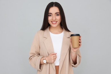 Photo of Young female intern with cup of drink on grey background