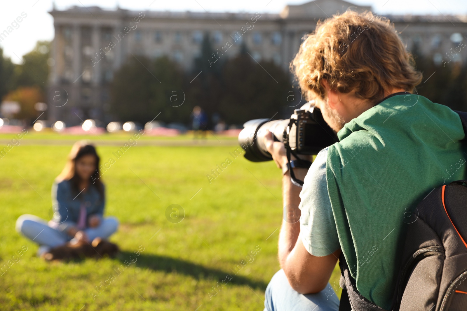 Photo of Male photographer taking photo of young woman with professional camera on grass outdoors