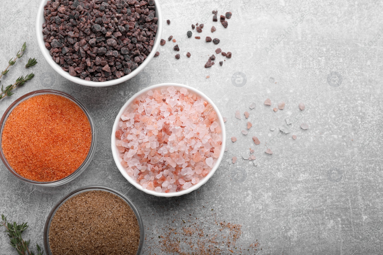 Photo of Different kinds of salt on grey table, flat lay. Space for text