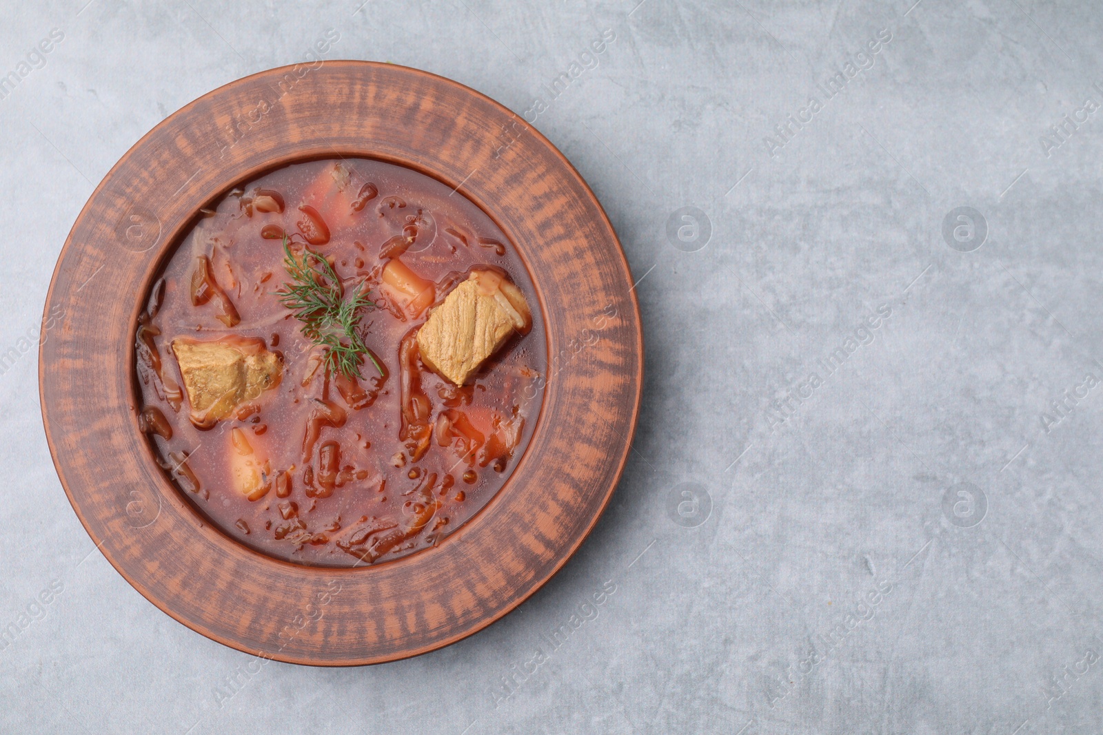 Photo of Bowl of delicious borscht on light grey table, top view. Space for text