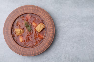 Photo of Bowl of delicious borscht on light grey table, top view. Space for text