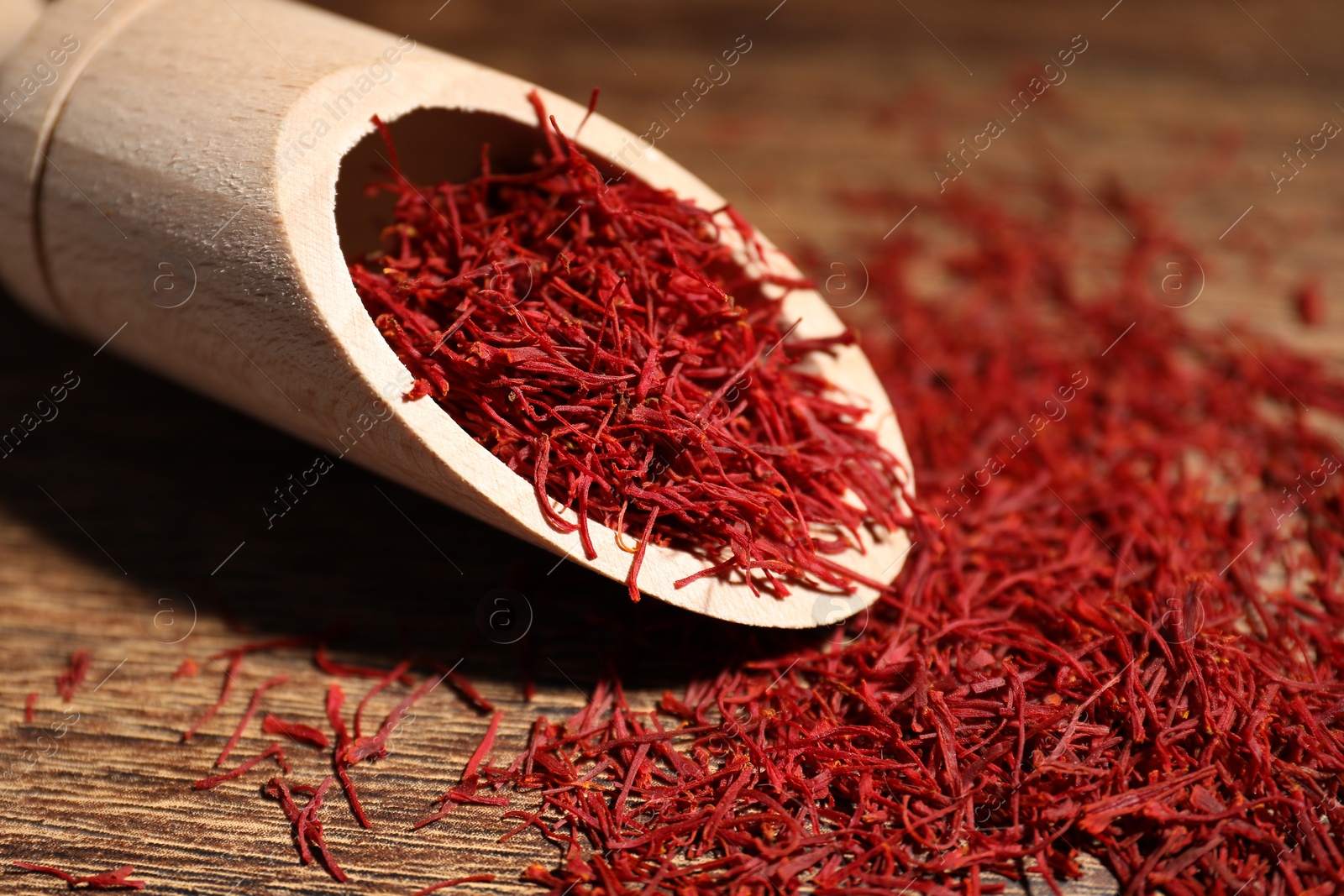 Photo of Aromatic saffron and scoop on wooden table, closeup