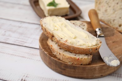 Photo of Slices of tasty bread with butter and knife on white wooden table, closeup. Space for text