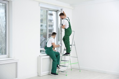 Construction workers installing plastic window in house