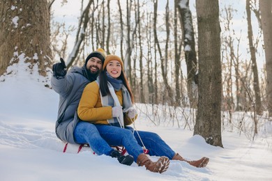 Happy young couple sledding outdoors on winter day