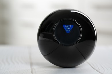 Magic eight ball with prediction Can't Say Now on light table, closeup