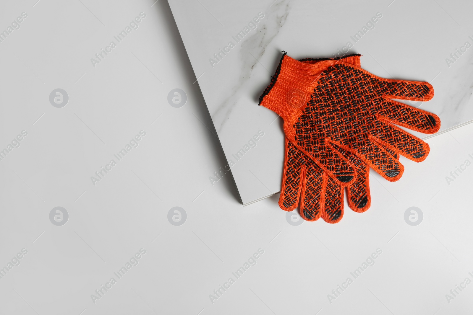 Photo of Ceramic tiles and gloves on white background, top view. Space for text