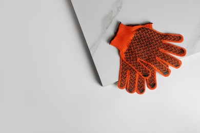 Ceramic tiles and gloves on white background, top view. Space for text
