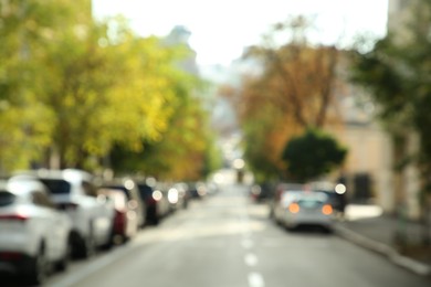 Photo of Blurred view of quiet city street with cars on road on sunny day