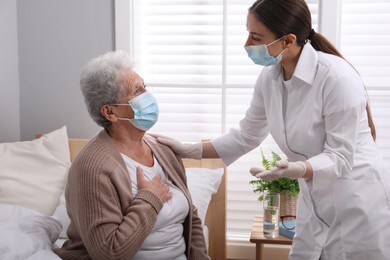 Doctor taking care of senior woman with protective mask at nursing home