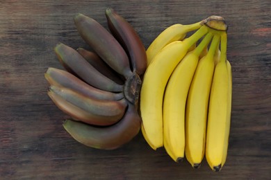 Tasty purple and yellow bananas on wooden table, flat lay