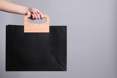 Photo of Woman holding paper shopping bag on grey background, closeup. Space for text