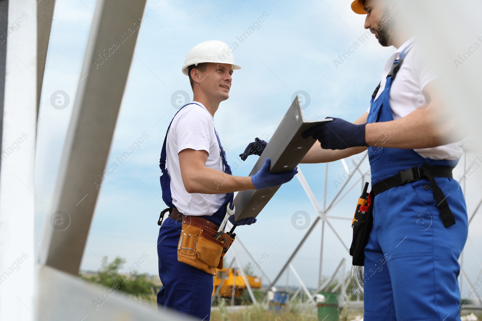 Photo of Workers building high voltage tower construction outdoors. Installation of electrical substation