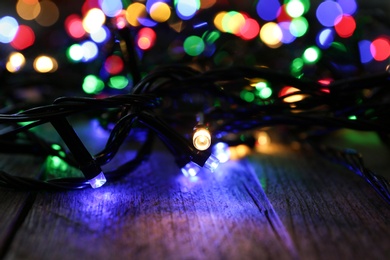 Photo of Colorful Christmas lights on wooden table, closeup view