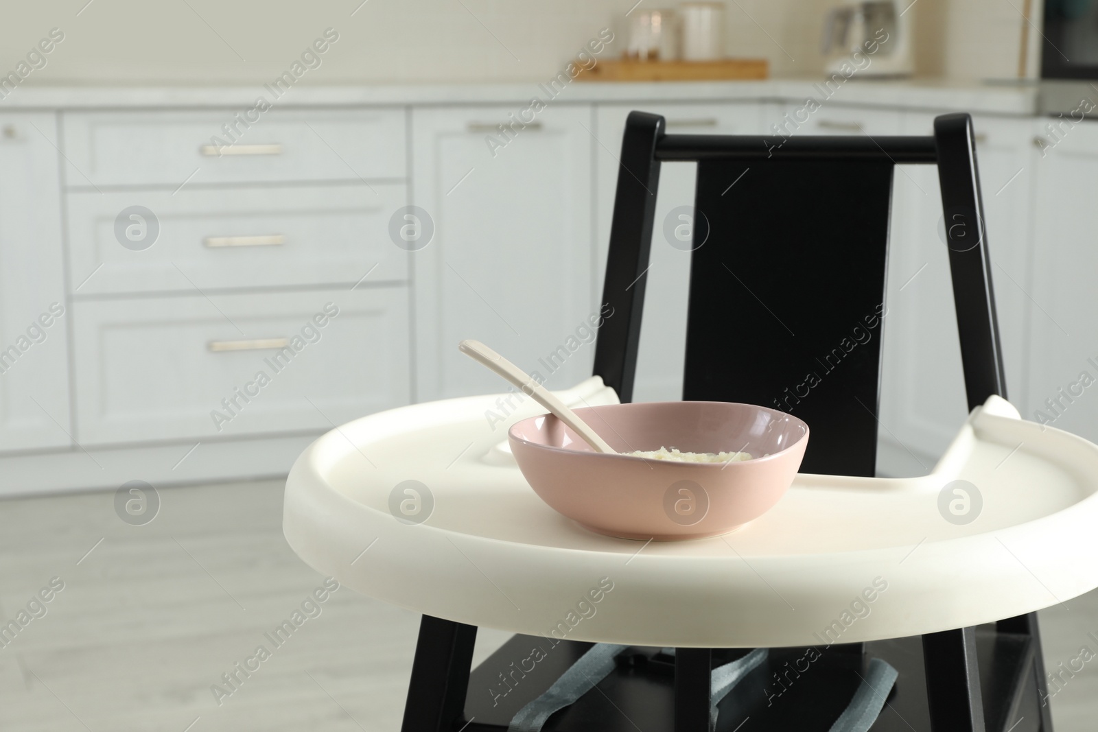 Photo of Baby high chair with healthy food in kitchen. Space for text