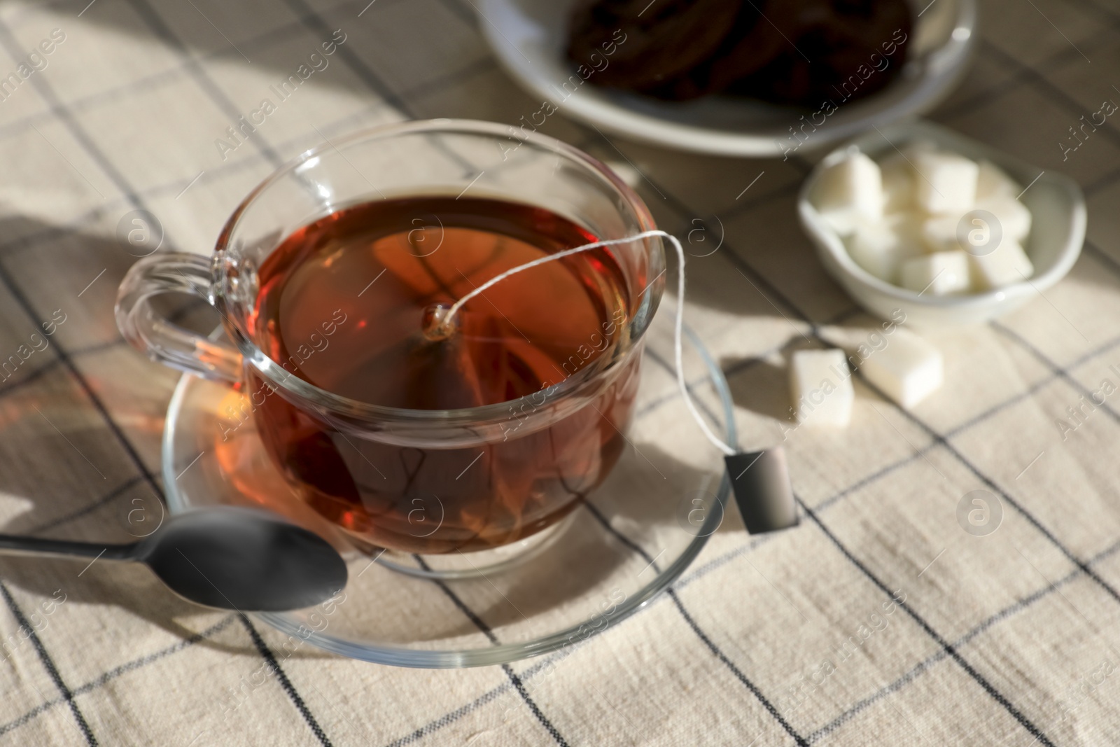 Photo of Tea bag in glass cup on table, closeup