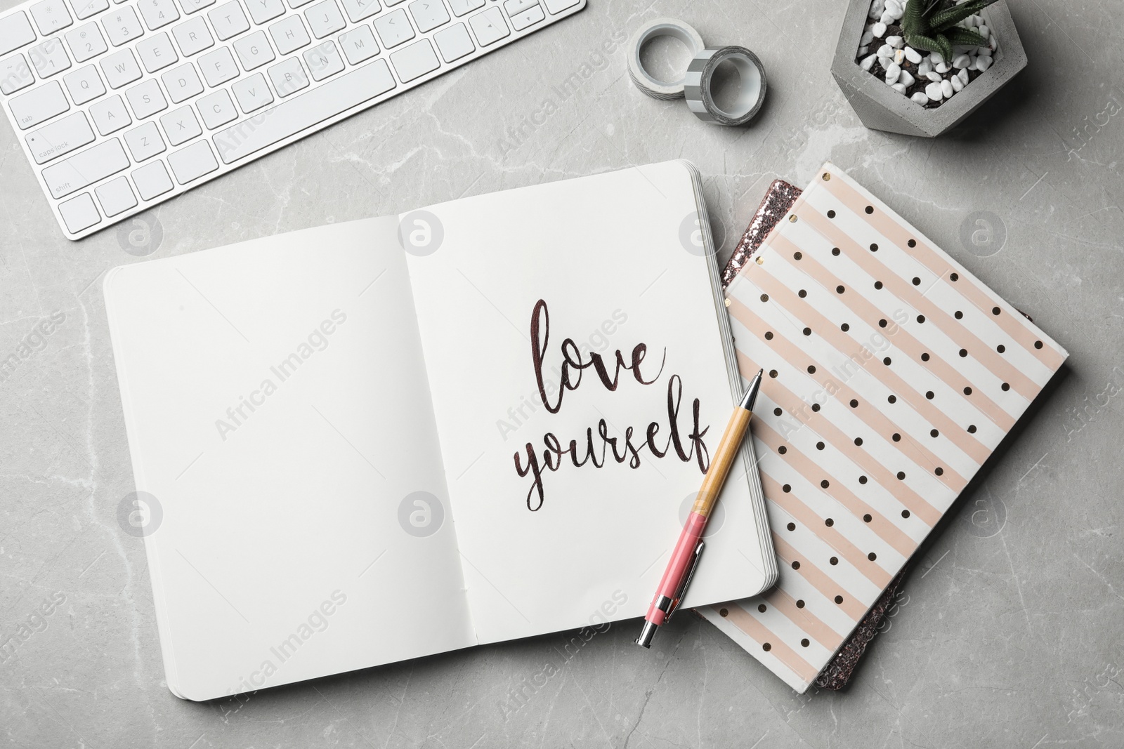 Photo of Flat lay composition with words LOVE YOURSELF written in notebook on grey table