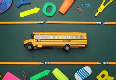 Photo of Flat lay composition with yellow school bus and stationery on green background. Transport for students