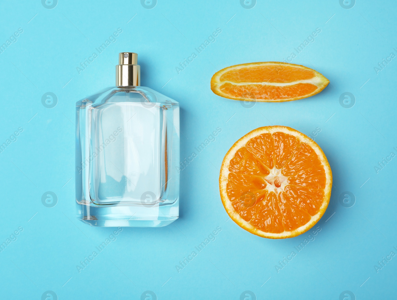 Photo of Bottle of perfume and orange on color background, top view