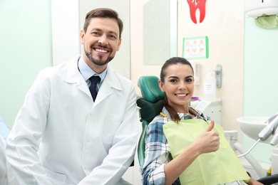 Professional dentist and happy patient in modern clinic