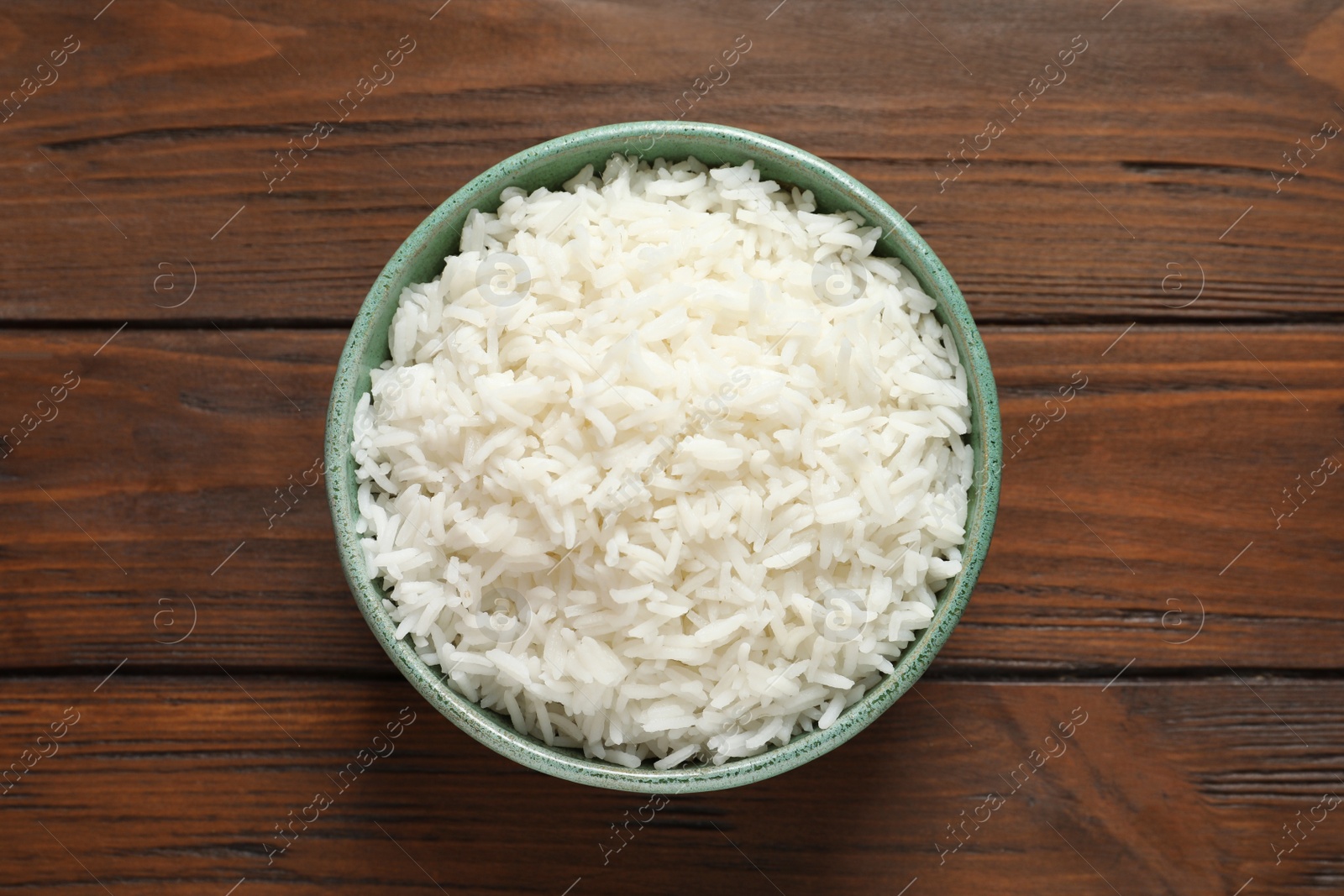 Photo of Bowl of tasty cooked rice on wooden background, top view
