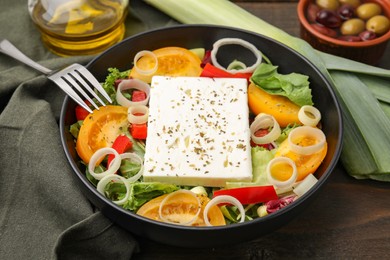Photo of Bowl of tasty salad with leek and cheese served on wooden table, closeup