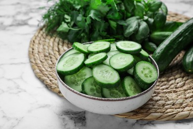 Photo of Fresh ripe cucumbers and greens on white marble table