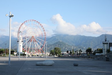 Photo of Batumi, Georgia - October 12, 2022: Ferris wheel and lighthouse in city near mountains