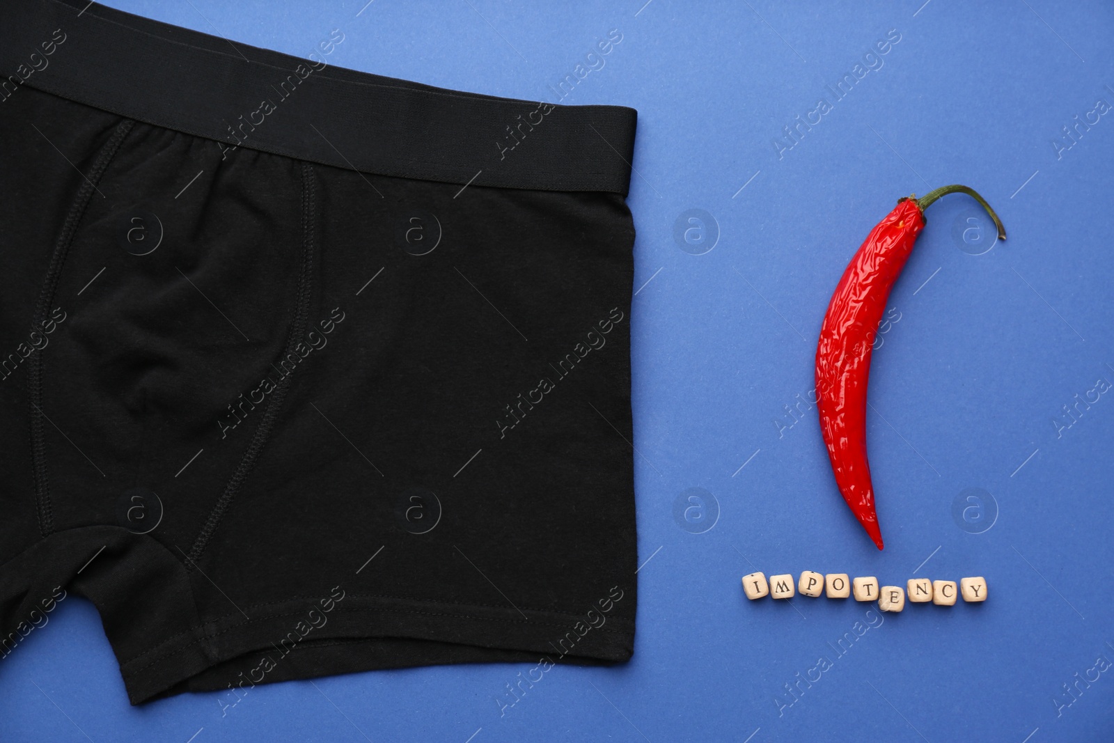 Photo of Men's underwear, chili pepper and word Impotency on blue background, flat lay