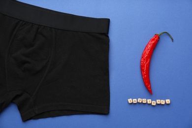 Photo of Men's underwear, chili pepper and word Impotency on blue background, flat lay