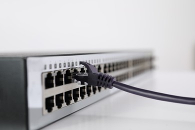 Closeup view of network switch with cable on light background, space for text. Internet connection