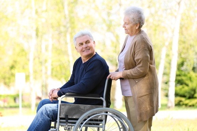 Photo of Mature man in wheelchair and senior woman at park on sunny day
