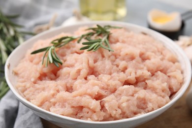 Fresh raw minced meat and rosemary in bowl on table, closeup
